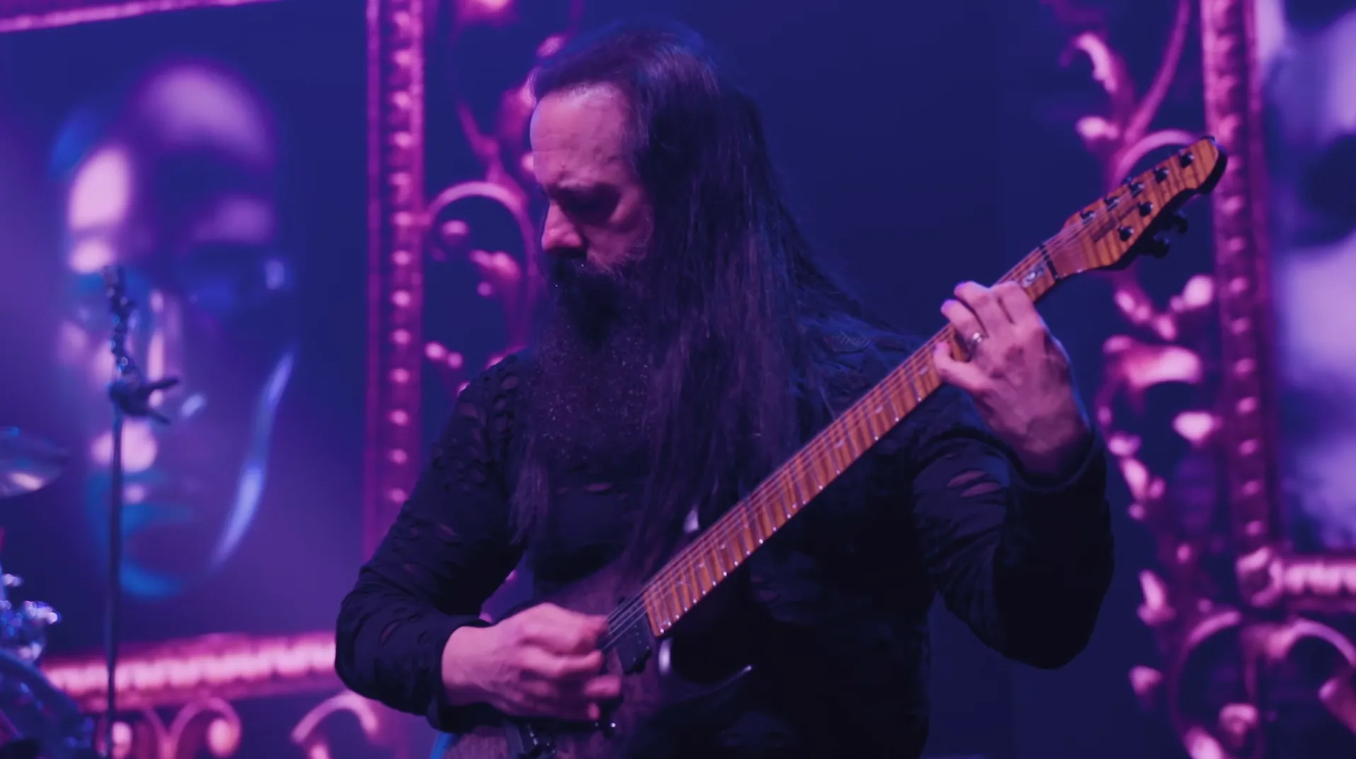 Dream Theater guitarist John Petrucci performing in front of purple live visuals